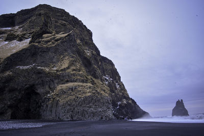 Rock formation by sea against sky