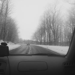 Cars on road against clear sky seen through car windshield