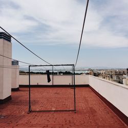 Clothesline on building terrace against sky