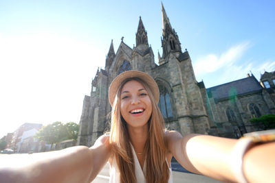 Smiling tourist girl takes self portrait in front of salford cathedral, manchester, england