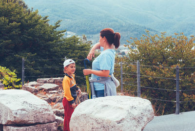 Mother and son standing by rocks against trees