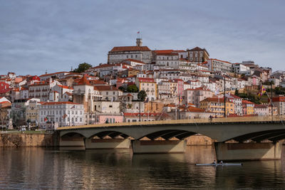 Bridge over river by buildings against sky in city