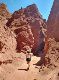 Full length rear view of woman walking towards mountain