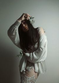 Young woman posing while standing against wall