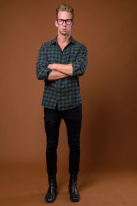 Portrait of young man standing against wall