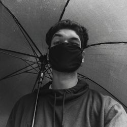 Close-up portrait of young man holding umbrella standing outdoors