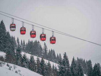 Low angle view of overhead cable car over snowcapped mountain against clear sky