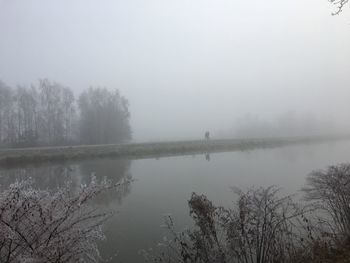 Scenic view of lake against sky during foggy weather