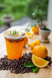 Black coffee top on fresh orange juice on wooden table