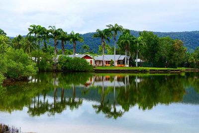 Reflection of trees and building in lake against sky