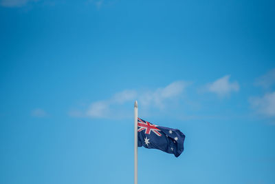 Low angle view of flag against blue sky