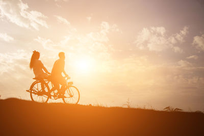 Silhouette man riding bicycle against sky during sunset