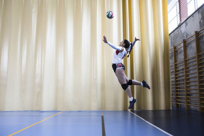 Professional female volleyball player in action serving ball