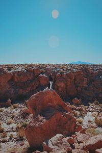 Man standing on rock against sky