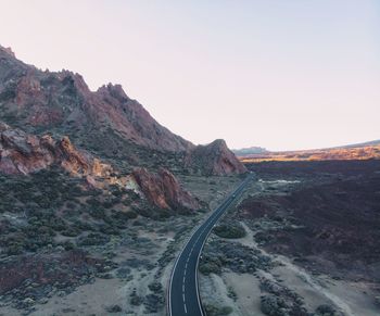 Road leading towards mountains against clear sky