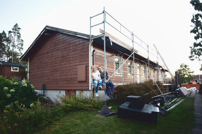 Happy couple sitting outside house being renovated