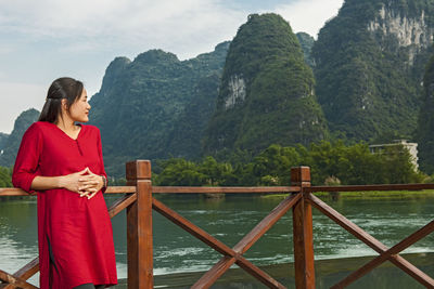 Beautiful woman resting her elbows on balustrade next to river li