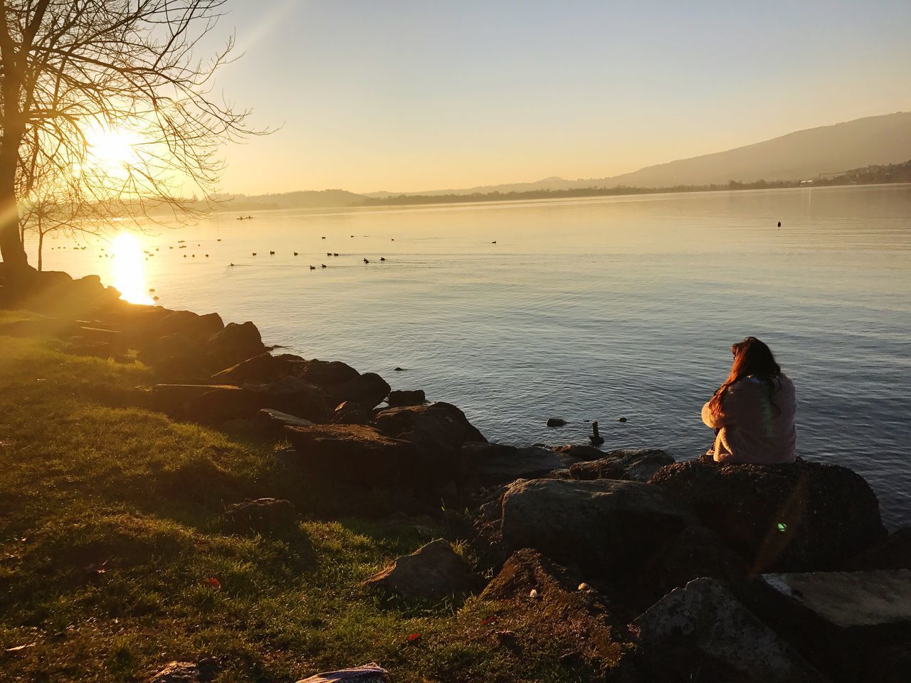 sunset, real people, water, nature, beauty in nature, sea, one person, sky, scenics, outdoors, tranquil scene, rock - object, leisure activity, women, sitting, horizon over water, tranquility, lifestyles, beach, standing, full length, clear sky, day, people