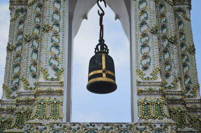 Low angle view of illuminated lamp hanging by building