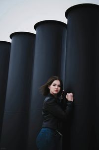Portrait of beautiful young woman standing by black columns