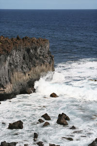 Scenic view of rocks in sea against sky