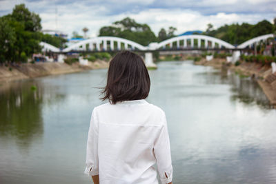 Rear view of woman standing on bridge over river