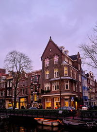 Buildings by canal against sky in city