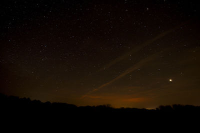 Silhouette landscape against star field at night