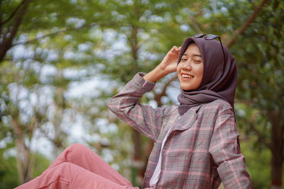 Young woman standing against trees