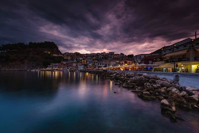 Scenic view of river by town against sky at sunset