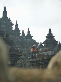 Man cleaning temple against sky