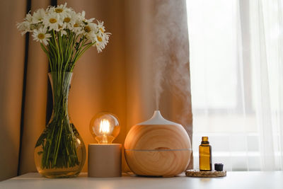 Aromatherapy concept. aroma oil diffuser on the table against the window.