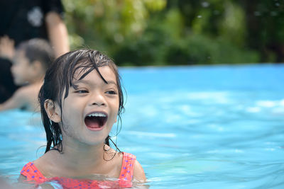 Cute girl with mouth open looking away while swimming in pool