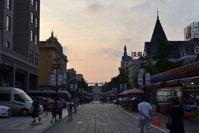 People on street amidst buildings in city against sky