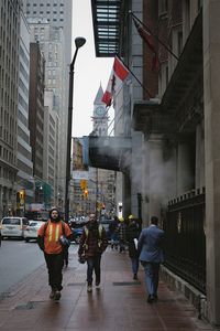 Rear view of people walking on street amidst buildings