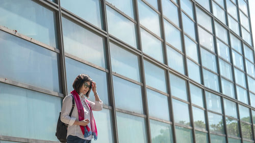 A woman standing before glass windows 