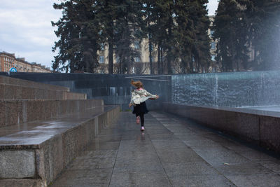 Happy little cute girl having fun in splashes a fountain