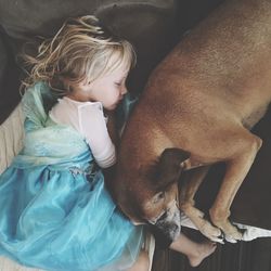 High angle view of girl sleeping on sofa by dog at home