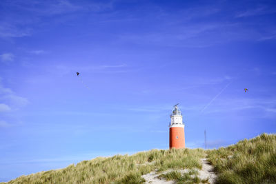 Bird flying over lighthouse against sky