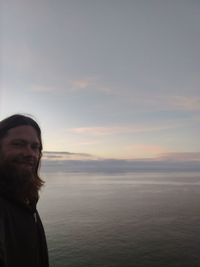 Portrait of smiling woman against sea during sunset