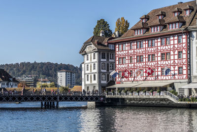 Buildings by river against clear sky