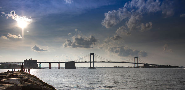 Bridge over sea against cloudy sky