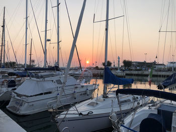 Sailboats moored at harbor during sunset