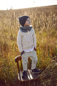 Fashionable boy child stand on a chair in autumn on the field