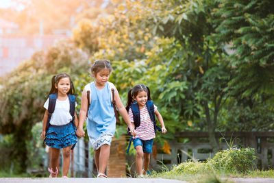 Smiling backpack siblings walking on road