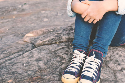 Low section of woman sitting on rock