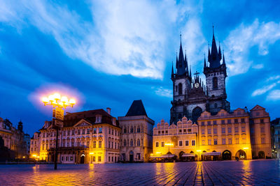 Illuminated building against cloudy sky