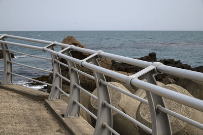 Railing on beach against clear sky