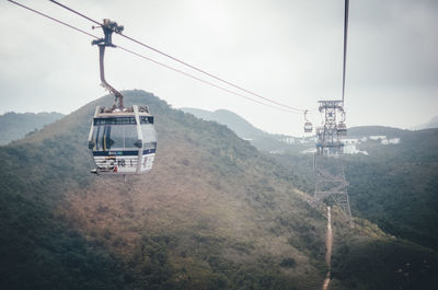 Overhead cable car over mountains against sky