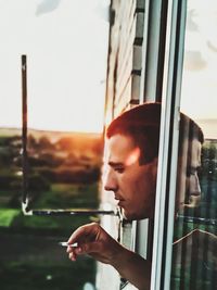 Portrait of young man looking through window